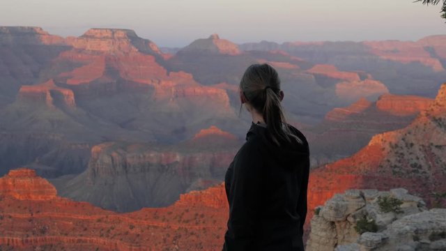 Slow motion shot of woman looking at gorge during sunset in Grand Canyon National Park in Arizona, USA