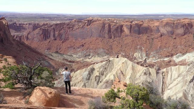 Young male tourist walking to viewpoint of Upheaval Dome crater in Canyonlands National Park in Utah, USA