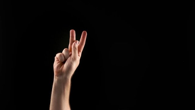 Hand showing letter K on dark background. Sign language alphabet