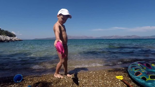 Caucasian boy toddler, playing on a deserted beach , located at Sesi, Attica, Greece, 60fps wide shot