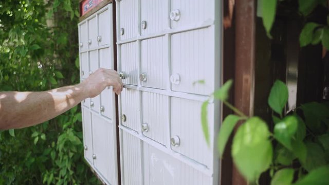 Side view of man unlocking mailbox removing mail and closing mailbox