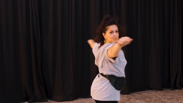 Curly Woman With Bag On Waist Dancing In The Studio - zoom shot