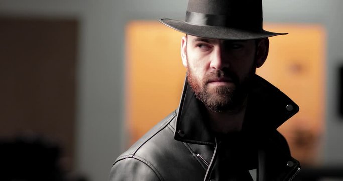 Shadowy man in hat looks up into camera, then behind him, then back to camera
