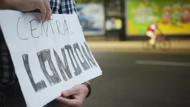 Close up hands of hitchhiker hold sign that says Central London