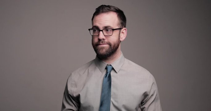 Awkward man looks up and anxiously cleans glasses with tie, medium shot