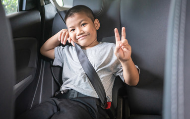 Asian boy fastened with safety seat belt in car.
