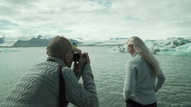 Female Posing to Photographer In Front of Icebergs in Jokulsarlon Lake, Iceland. People on Sighteeing of Icelandic Landmark