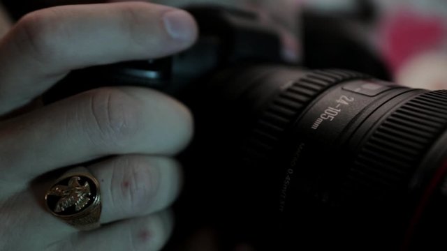 Photographer With Men's Ring On His Finger Rotates The Focus Ring Before Clicking The Flash Button Of A DSLR Camera - extreme close up