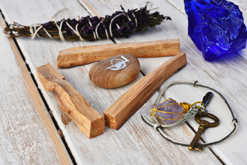 A close up image of three pieces of palo santo smudge sticks with a home made pendulum and reiki symbol. 