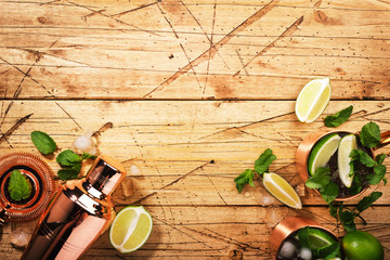 Moscow mule cocktail in copper mug with lime, ginger beer, vodka and mint. Wooden table, top view, copy space