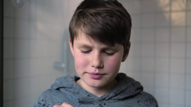 Young handsome caucasian boy removing mouth plate retainer in the bathroom