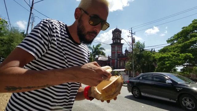 Man enjoying a fresh Coconut at the Queen's Park Savannah in Trinidad and Tobago