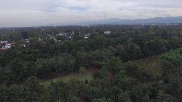 Vista a&eacute;rea sobre los Viveros en Coyoac&aacute;n, Ciudad de M&eacute;xico, el drone volando hacia atr&aacute;s para descubrir el skyline de la ciudad.