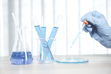 Scientists hold the pipette and drop the blue chemical liquid for research and analysis in a laboratory