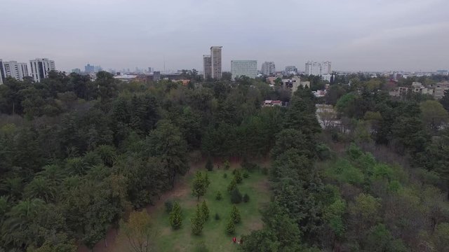 Vista a&eacute;rea sobre los Viveros en Coyoac&aacute;n, Ciudad de M&eacute;xico, el drone volando hacia atr&aacute;s para descubrir el skyline de la ciudad.