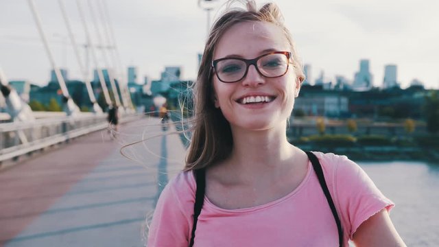 Portrait of beautiful caucasian woman with glasses and toothy smile standing on the bridge 