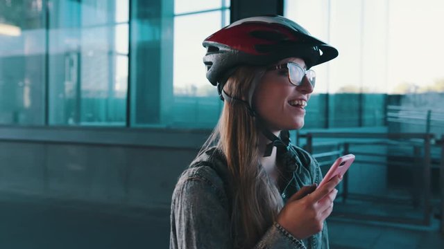 Happy caucasian woman with helmet rollerblading through the city and checking the app on the smartphone