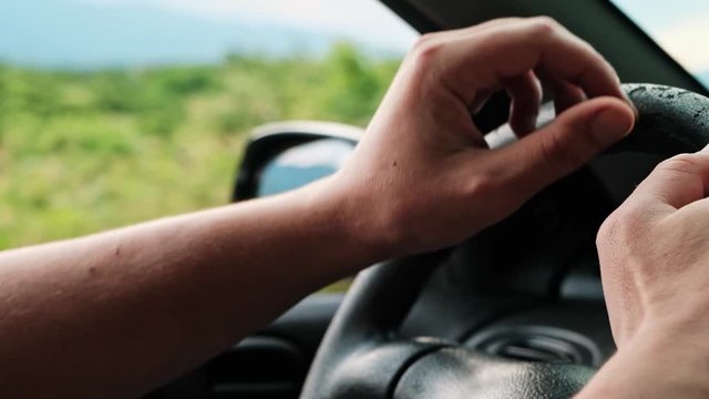 Detail close up of a mans hands driving the car in slow motion.
