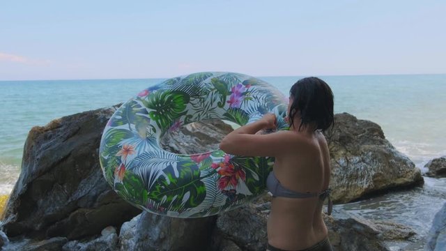 Young woman smiling and happy enjoying a day out at the seaside with her inflatable ring. 