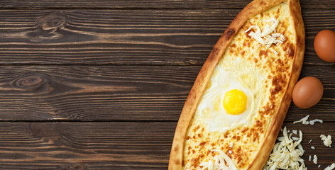 Turkish flatbread (pide). Top view, copy space for text. Pide is a very delicious dish of Turkish cuisine, which is an open flatbread on yeast dough of a boat with cheese filling and egg in the form