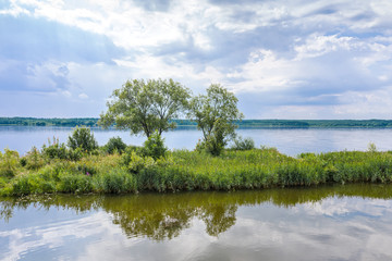 small island with green trees on Vileyka water reservoir, Belarus. aerial landscape in cloudy summer day