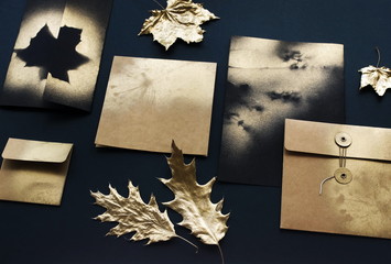 Autumn background. greeting cards mockup template, invitations blank in black, gold colors and fall gold leaves on black textured background. Flat lay, top view, copy space