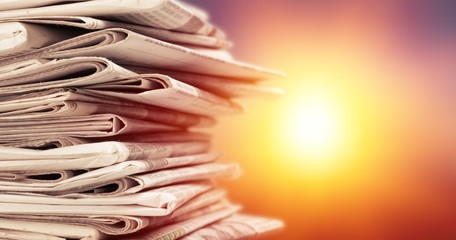 Pile of newspapers stacks on blur sunset background