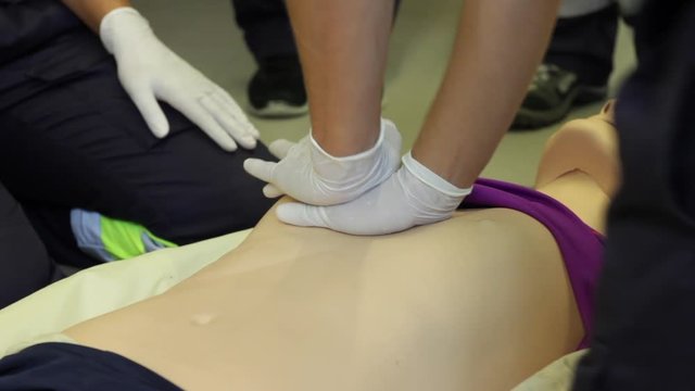 Close up of male hands making CPR (Cardiopulmonary resuscitation) on a plastic dummy. Cardiac massage during a first aid class.