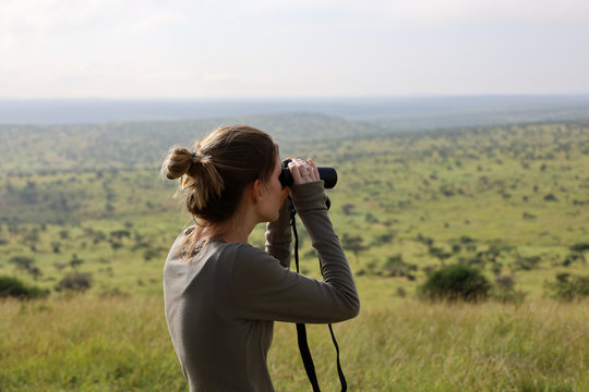 Woman looking through binoculars on safari in Kenya, Africa