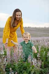 Young mother with a baby on a lavender field background. Happy family leisure outdoors.