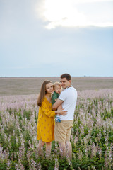 Young family with a baby on a lavender field background. Happy family leisure outdoors.