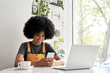 Smiling African American young hipster mixed race gen z teenage girl with Afro hair holding smart...