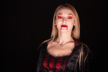 Evil vampire woman with blond hair over black background. Halloween outfit.
