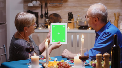Old retired senior couple using green mock-up screen digital isolated tablet computer. Aged people...