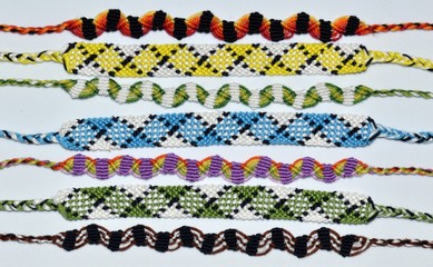 Multi-colored woven friendship bracelets handmade of embroidery bright thread with knots on light...