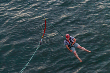 Rope jumping from high altitude of bridge. Bungee jumping from pedestrian bridge over beautiful river