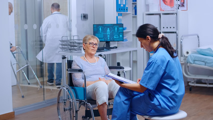 Obraz premium Elderly patient with walking disabilities in wheelchair seeking medical advice in recovery clinic or hospital. Senior handicapped woman health care support medical insurance paralyzed person