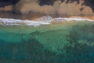 Aerial shot of ocean water with sandy beach. Amed, Bali, Indonesia