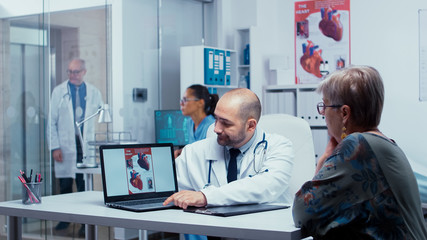 Doctor presenting potential heart problems to old retired elderly patient. Heart disease problems...