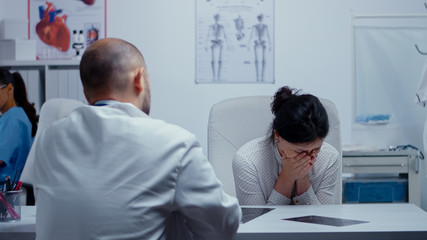 Woman starts crying at doctor after hearing bad news about her or other dear person health. Bad news about terminal patient. Cancer or other terminal ill concept