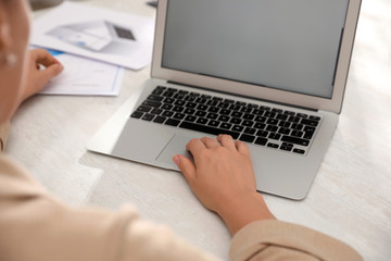 Woman working with laptop at table in office, closeup