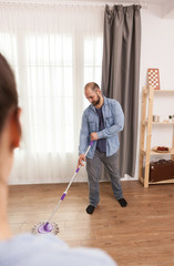 Boyfriend mopping the floor in living room.
