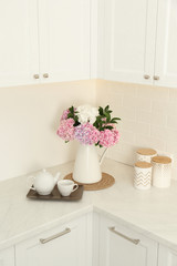 Fototapeta na wymiar Beautiful bouquet of hydrangea flowers and tea on light countertop