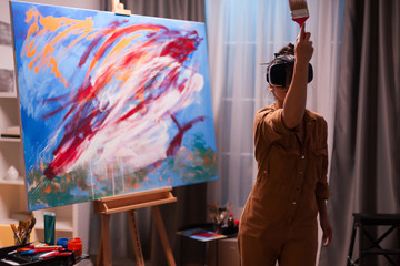 Talented painter with vr headset painting a masterpiece on canvas in art studio. Modern artwork paint on canvas, creative, contemporary and successful fine art artist drawing masterpiece