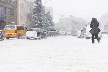 Adult man passing the winter city road in heavy snowy storm.