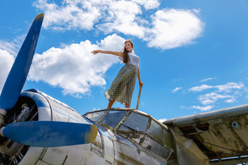 Pretty young adult woman stands on an abandoned plane