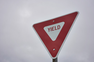 Yield sign against overcast sky background. A give way sign which indicates that merging drivers...