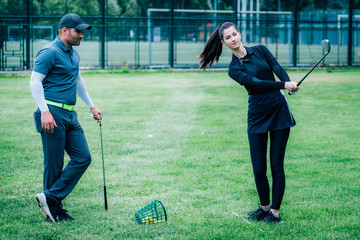 Individual golf lesson. Young woman having a golf lesson with golf instructor