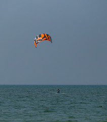 A surfboard is surfing on the sea near the long bridge in Pattaya beach of eastern in Thailand on a long holiday.