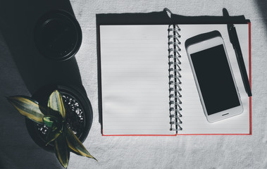 Workspace with mobile phone,notebook,pen,coffee cup and house plant on white background,top view